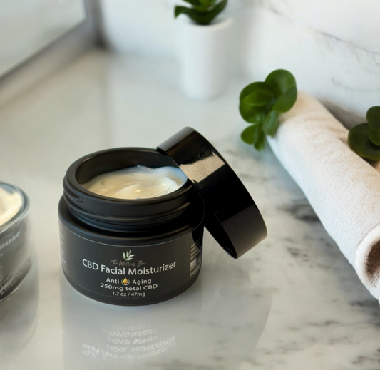 CBD facial moisturizer jar on a marble surface with plants in the background