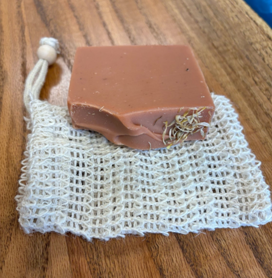 Bar of soap on a natural fiber soap bag on a wooden surface