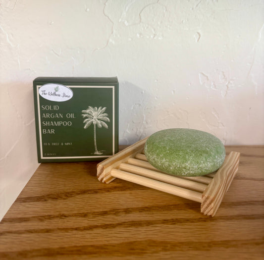 Bar shampoo on soap dish with the box showing it comes from The Wellness Store