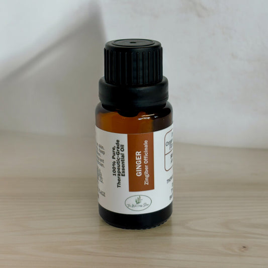 Ginger essential oil on a wood surface with a blurred wall in the background