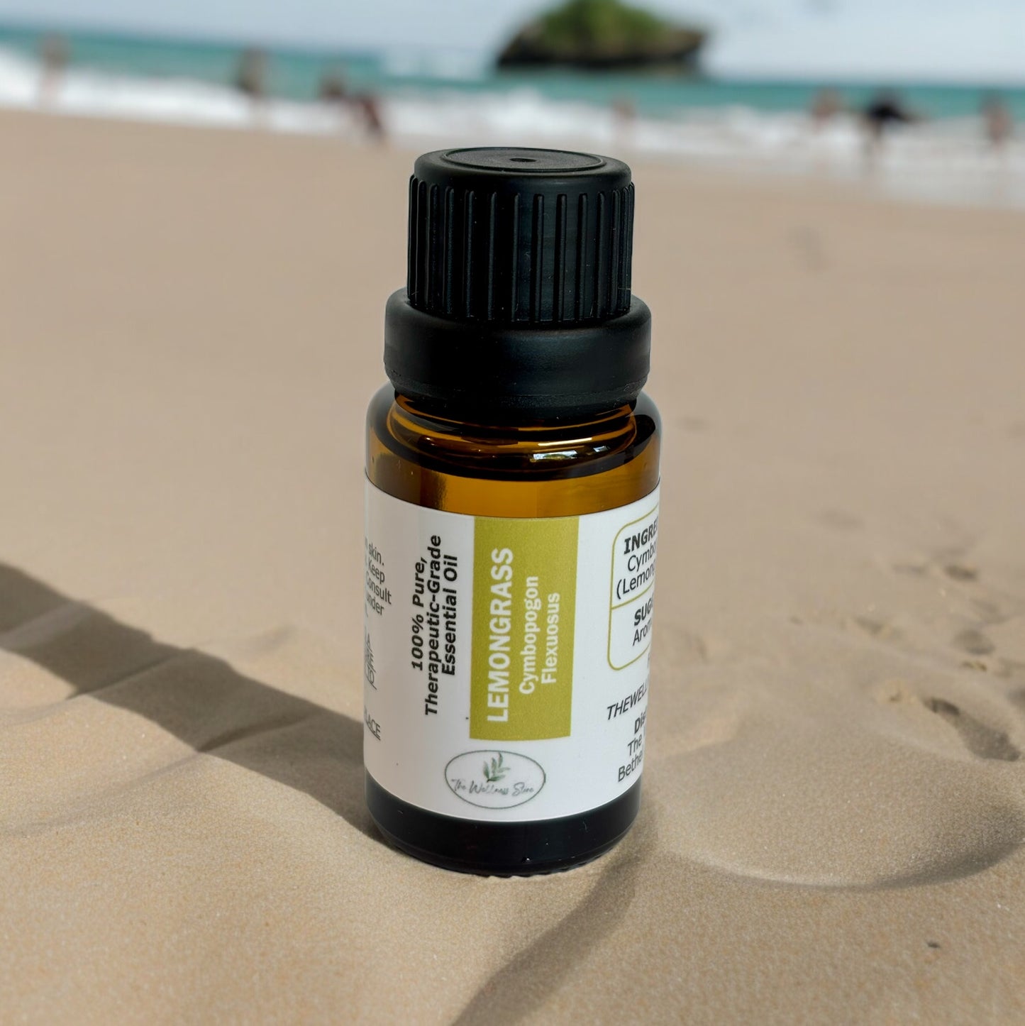 lemongrass essential oil on sand with the water blurred in the background