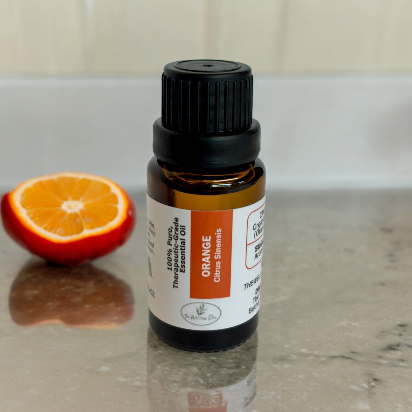 Orange essential oil o a marble counter with an orange in the background