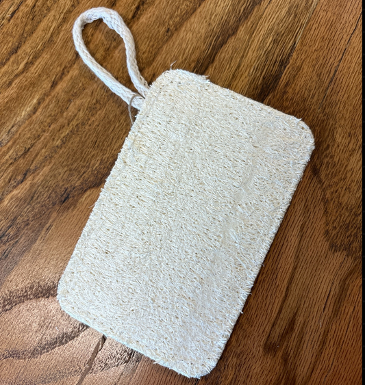 Rectangular white scrubber with a handle on a wooden surface