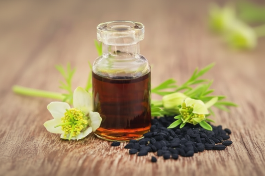 Black cumin seed oil bottle with Nigella sativa flowers and seeds - traditional herbal remedy with modern health research