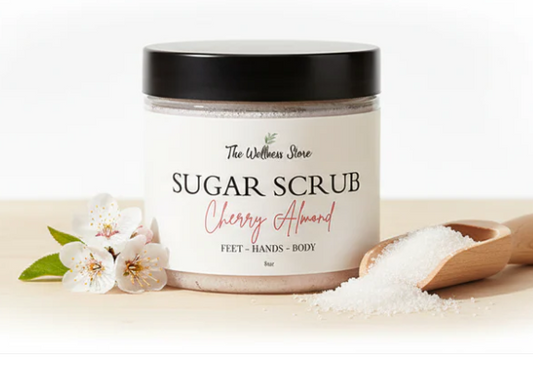 Jar of cherry almond sugar scrub with a wooden scoop and flowers on a light background