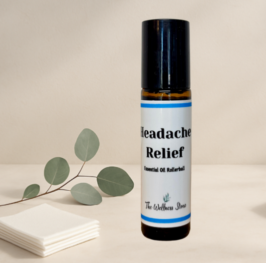 Rollerball labeled 'Headache Relief' from 'The Wellness Store' on a neutral background with eucalyptus leaves.
