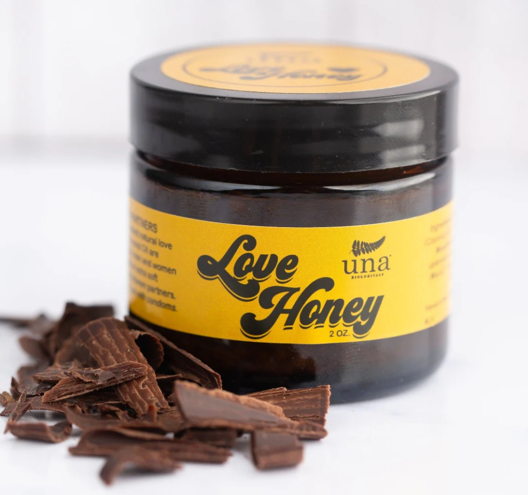 Love Honey balm on a white background with chocolate shavings next to it