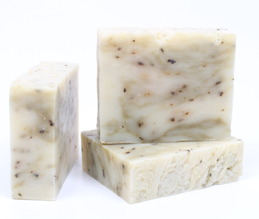 Three bars of natural soap with visible specks on a white background